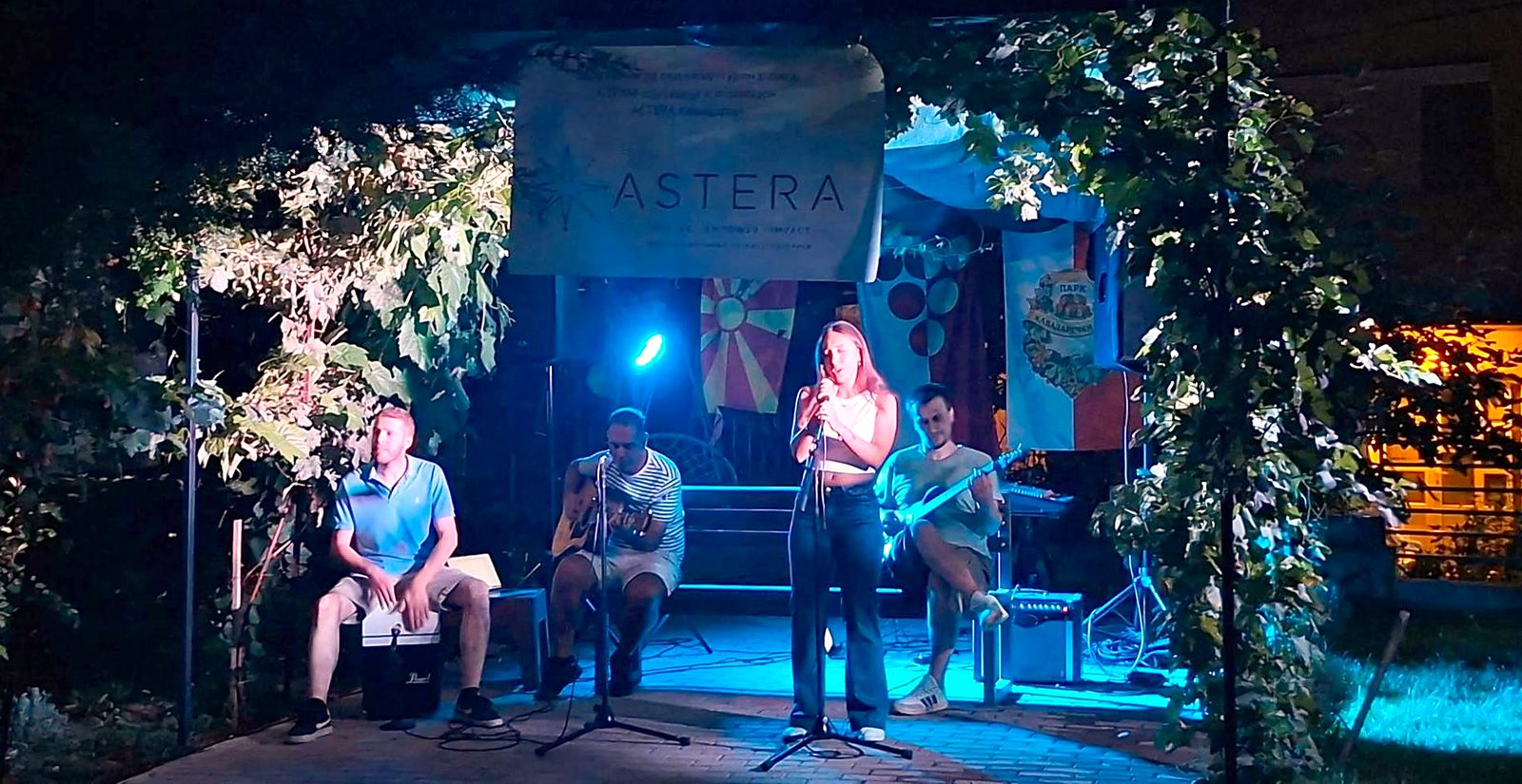 A singer and three musicians on stage under the ASTERA banner